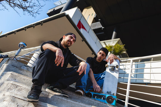 Two friends listening to music on a boombox, embracing hip hop and youth culture