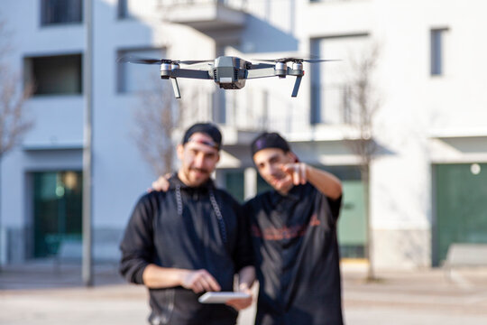 Young men operating a drone with remote control tablet in an urban setting during the day