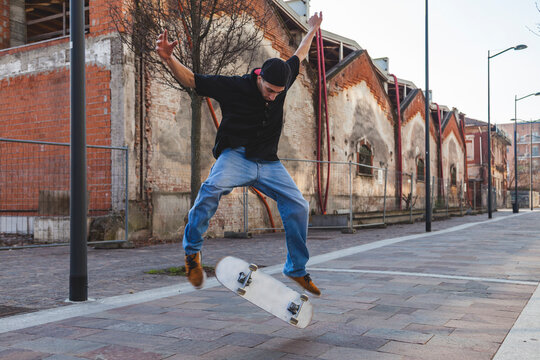 Skateboarder performing an ollie trick jumping with his skateboard in urban street
