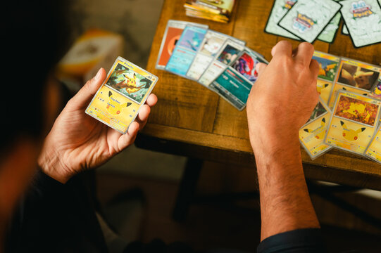 Chicago, IL/USA - September 19, 2026: A person holds and sorts Pikachu trading cards from the Pok&eacute;mon 30th Celebration set while additional collectible cards are arranged across a wooden table
