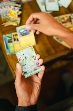 Chicago, IL/USA - September 19, 2026: A person reveals a rare collectible Pok&eacute;mon trading card while sorting through cards from the 30th Celebration set at a wooden table