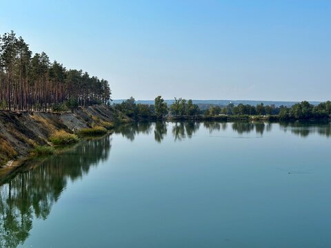 Wide Angle View of Serene Quarry Lake with Pine Forest Reflections