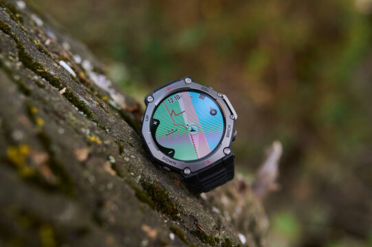 Rugged smartwatch with GPS navigation map lying on a mossy stone outdoors