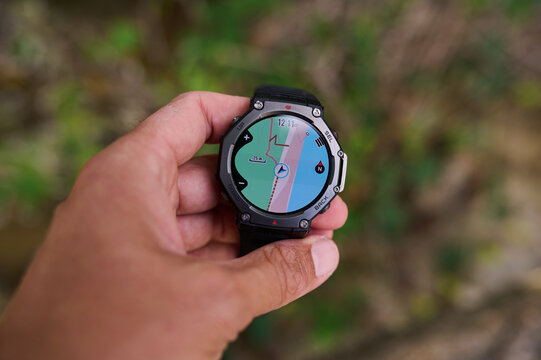 Hand holding smartwatch with GPS navigation map during outdoor hiking