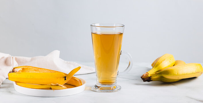 Banana peel tea in a glass and bananas on the table web banner