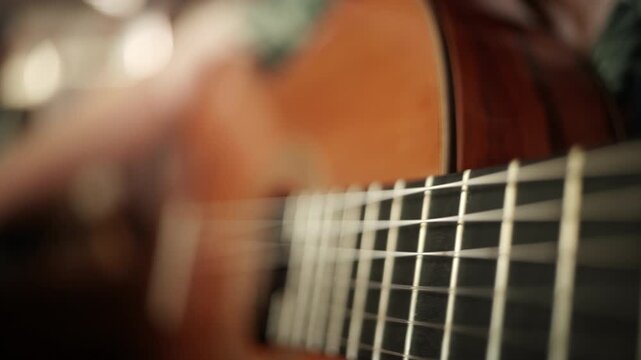 Cinematic close-up shot of a female musician's hand fingerpicking the nylon strings of a classical acoustic guitar, warm golden tones, shallow depth of field, sound hole and fretboard in soft focus