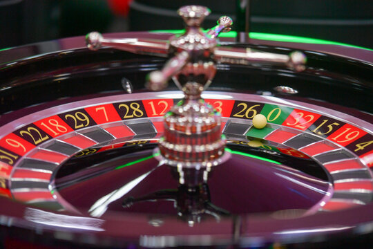 Close-up of a luxury casino roulette wheel with the white ball on the winning green zero pocket, featuring dramatic neon lighting for exciting high-stakes gaming concepts.