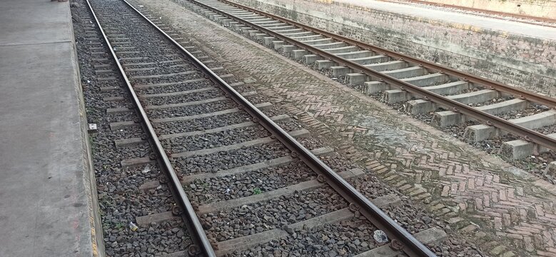 Converging railway tracks at a train station platform with railway infrastructure train rails public transport commuter travel platform edge rail system