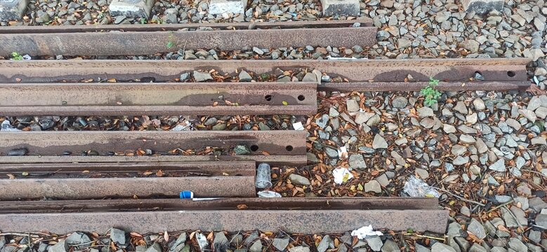 Top down view of weathered wooden railway sleepers and rusted tracks with railroad ties train tracks rusty railway infrastructure stone ballast