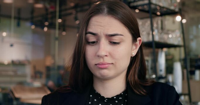 Skeptical woman displays hesitation in virtual interaction setting. Puzzled female ponders difficult situation with pensive facial expression, showing uncertain emotions during dialogue.