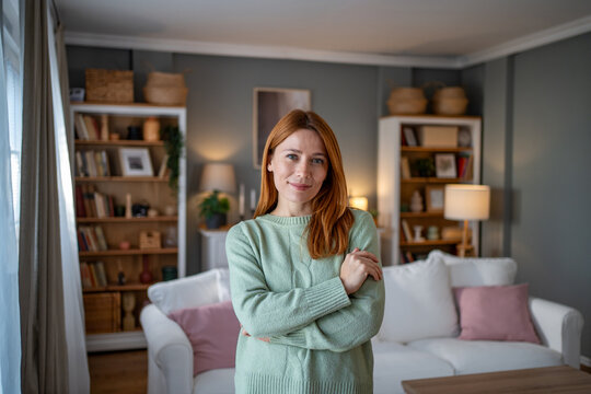 Redhead woman in green sweater smiling at home