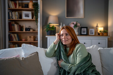 Redhead woman relaxing on couch in cozy living room © Migma_Agency