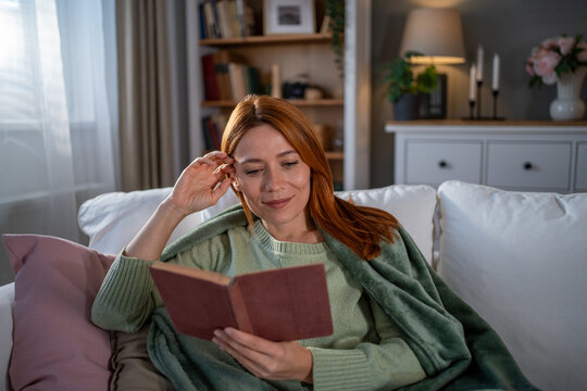 Woman reading book relaxing at home on sofa
