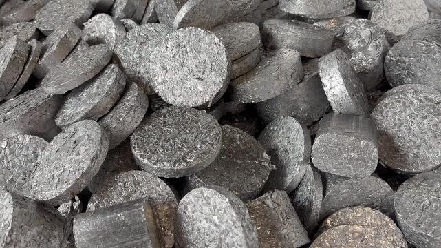 Zooming into a heap of aluminium pucks, compressed shavings from a lathe ready for recycling