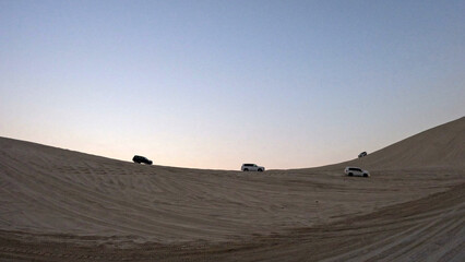 Four 4x4 SUVs Dune Bashing on a Tall Sand Dune Ridge at Dusk in the Qatar Desert © Kaitlind