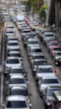 Bokeh view of road traffic near Chong Nonsi BTS skytrain station in Silom district, Bangkok, Thailand. Blurred background vertical footage.