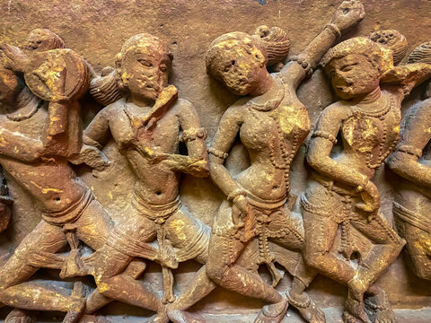 An ancient stone relief depicting Hindu deities. A detailed sculpture depicting Shiva with a third eye and Parvati seated nearby.