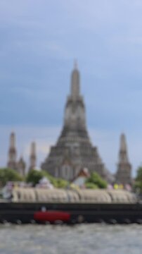Bokeh view of Buddhist temple Wat Arun on the banks of the Chao Phraya river, Bangkok, Thailand. Blurred background vertical timelapse footage.