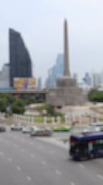 Bokeh view of road traffic near Victory Monument square, Bangkok, Thailand. Blurred background vertical footage.