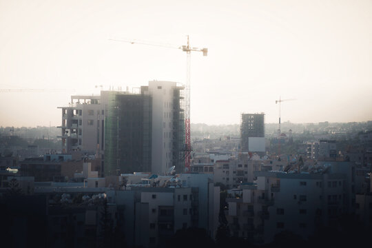 Silhouettes of tower cranes against sun. Limassol, Cyprus