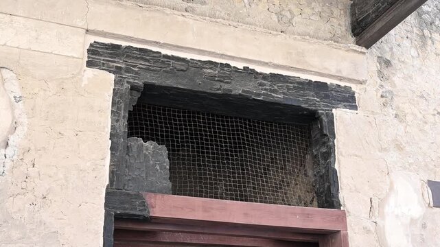 ERCOLANO, ITALY - SEPTEMBER 20, 2026: Carbonized wooden door frame preserved inside an ancient Roman house in Herculaneum, extraordinary evidence of pyroclastic surge preservation from the 79 AD Mount