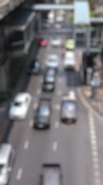 Bokeh view of road traffic near Asok BTS skytrain station, Bangkok, Thailand. Blurred background vertical footage.