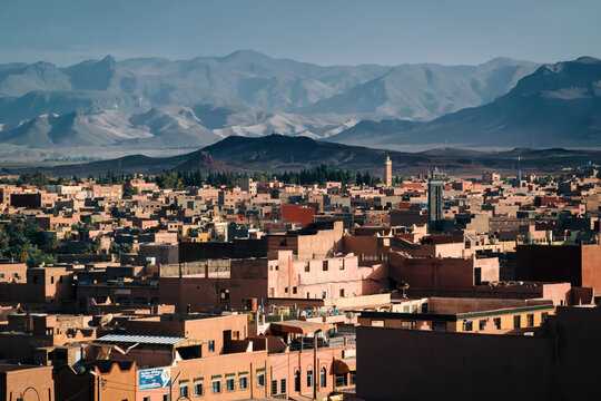 Tinghir buildings creating a traditional cityscape, extending towards arid atlas mountains under a clear blue sky