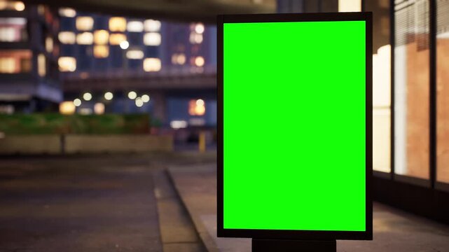 Vertical green screen citylight sign on a downtown sidewalk at dusk as the city lights come on, clear sky. Time lapse of city traffic, bokeh lights and moving cars. Clean chroma key area for