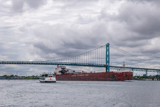 A Canada Steamship Lines freighter and boat transit the Detroit River near Ambassador Bridge, illustrating cross-border supply chains and North American trade and tariff negotiations. July 2026