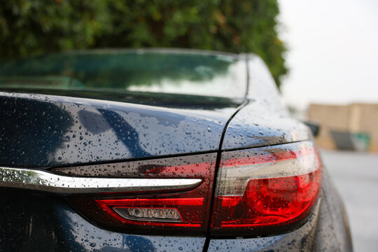 Close up of raindrops on black car side window and mirror during rainy weather, ideal for automotive