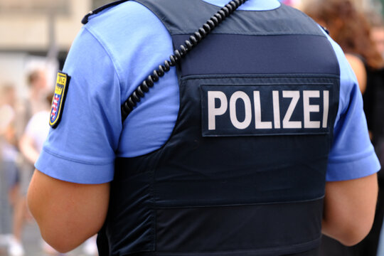 German police officer on duty in public place, uniformed policeman patrolling streets, public safety, law enforcement, urban patrol, security presence, Shoulder detail, law enforcement