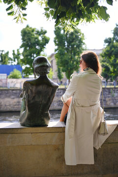 Berlin Germany Woman viewing bronze sculpture beside canal