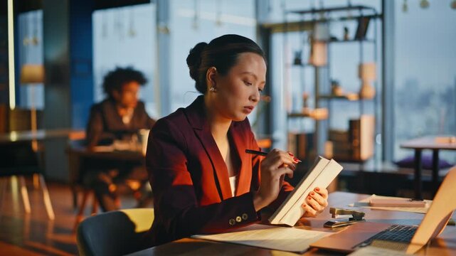 Businesswoman writing notes notepad evening office. Asian manager smiling work.