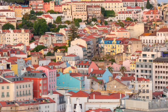 Dense urban view of Lisbon with colorful residential buildings and traditional red tiled rooftops, Portugal.