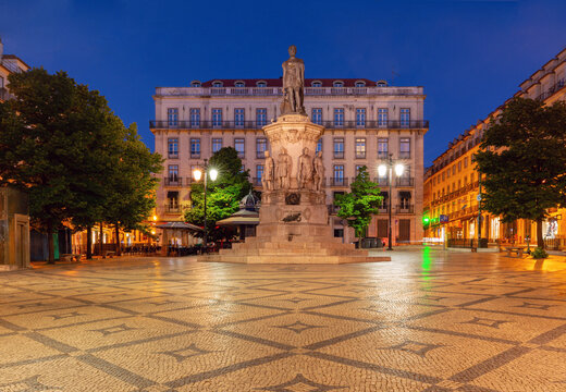 Monument to Luis de Camoes surrounded by historic buildings during blue hour in central Lisbon, Portugal.