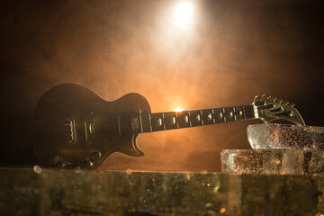 Music Concept: Guitar Miniature on a Dark Background with Vivid Light, Smoke, and Fire Effects. Golden electro guitar under a Dramatic Spotlight. © zef art