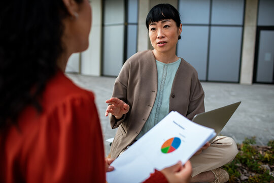 Two businesswomen discussing financial report outdoors
