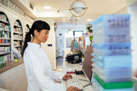 Pharmacist working on computer at modern pharmacy counter