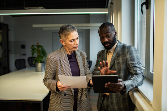 Two business professionals discussing project on tablet in modern office