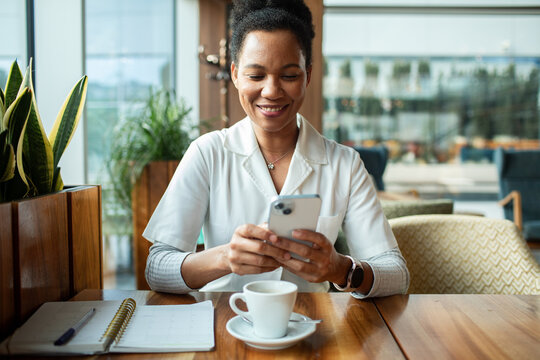 Smiling professional woman using smartphone at cafe table