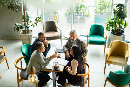 Senior colleagues discussing strategy in modern cafe lounge