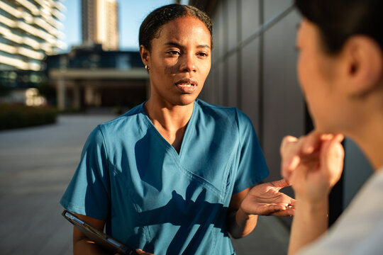Concerned nurse talking with colleague outside hospital