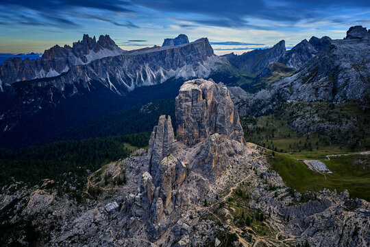 Aerial view of the iconic Cinque Torri rock towers surrounded by hiking trails and rugged alpine terrain, with Croda da Lago and Lastoi de Formin rising behind in the Italian Dolomites.
