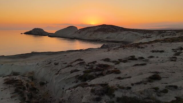 Early morning sunlight during a beautiful sunrise over the Aegean sea seen from the shore of Mandrakia on the Greek island Milos in Greece. Unique landscape on the coastline, natural blue ocean water