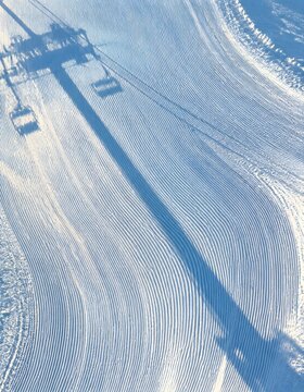 Aerial view of freshly groomed ski slope corduroy with fine parallel grooves curving down