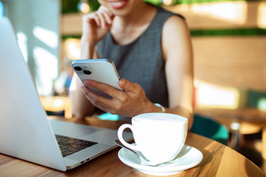 Businesswoman using smartphone and laptop at cafe