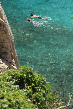 People snorkeling in turquoise waters in Calanque d'En-Vau in Calanques National Park, Cassis, France