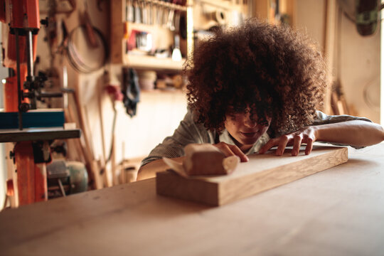 Focused carpenter checking wooden plank in workshop