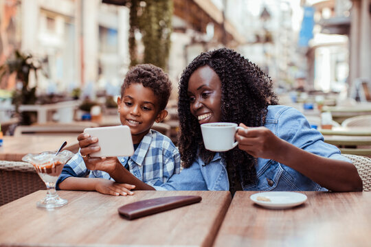 Mother and son watching smartphone at outdoor cafe
