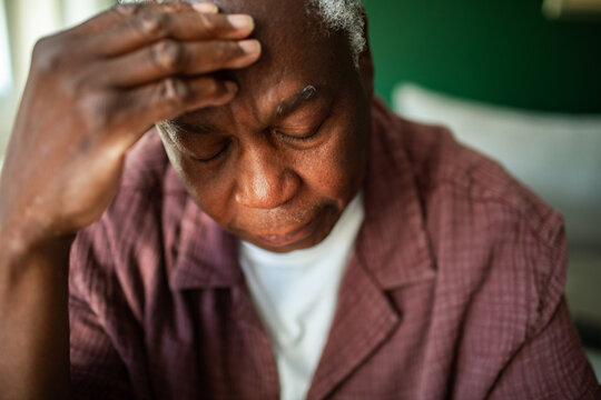 Stressed senior man touching forehead at home
